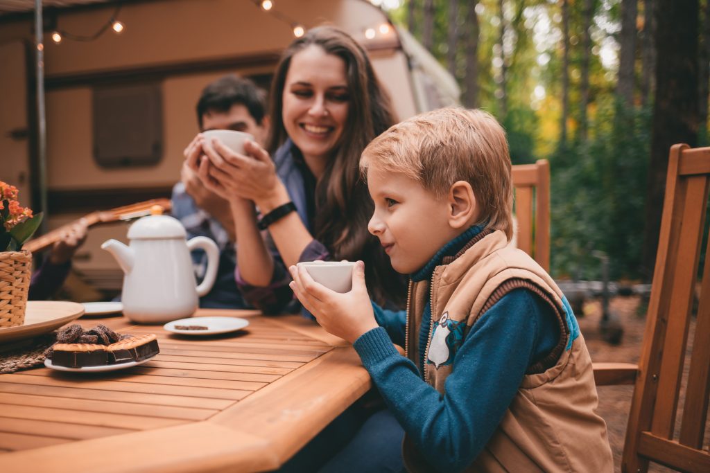 Happy family on a camping trip relaxing in the autumn forest.