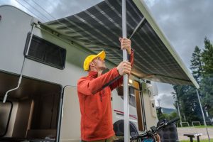 Man setting up RV awning for Summer RV camping